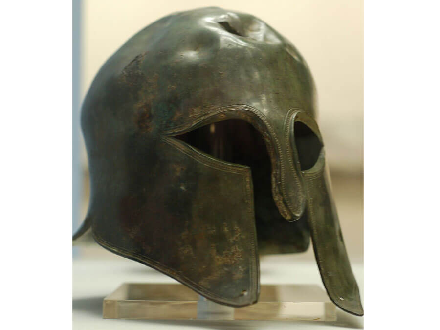 Bronze helmet of Corinthian type, with nail-holes in the top and cheek-pieces which show that it has been a trophy or victory offering. Exhibited at the British Museum