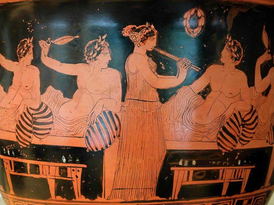 Symposium scene: men playing the kottavos game while a hetaira plays the aulos. Attic red-figure bell-krater.